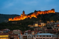 Aerial night view of Old Tbilisi Georgia with Illuminated Castle and cloudy blue sky