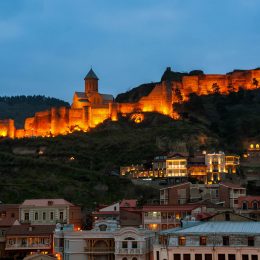 Aerial night view of Old Tbilisi Georgia with Illuminated Castle and cloudy blue sky